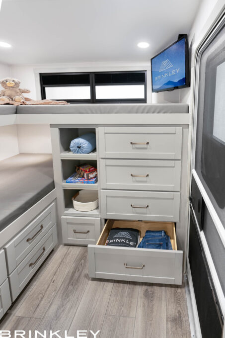 Integrated bunk bed ladder and dresser in a Brinkley Model Z 2810 Fifth Wheel, featuring four storage cubbies built into the steps and a white four-drawer dresser for maximum organization.