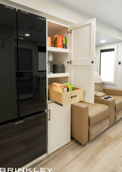 | Model I 235 Travel Trailers 12 Large pantry and 12v refrigerator in the Brinkley Model I 235, showcasing the high-quality construction of the best built travel trailers. The pantry features solid hardwood cabinetry with heavy-duty pull-out dovetail drawers, offering residential-style smart storage next to a premium high-capacity freezer.