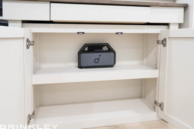 Portable Soundcore Bluetooth speaker stored in a dedicated hutch bracket inside a Brinkley Model Ix 20x travel trailer