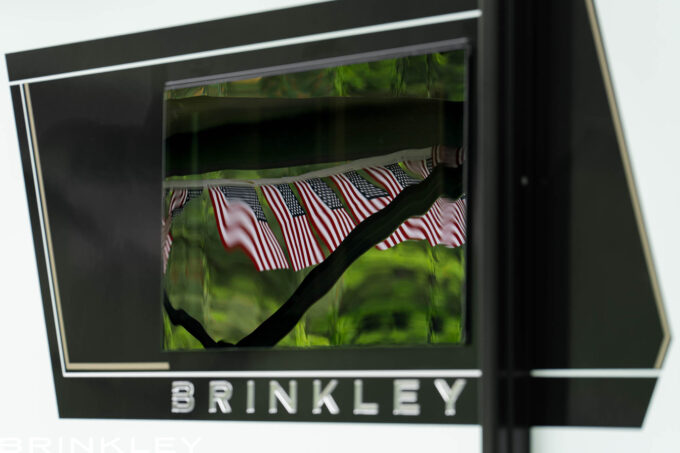 Luxury Travel Trailer Modern Square Frameless Windows with reflection of US flags at a campground during 4th of July.